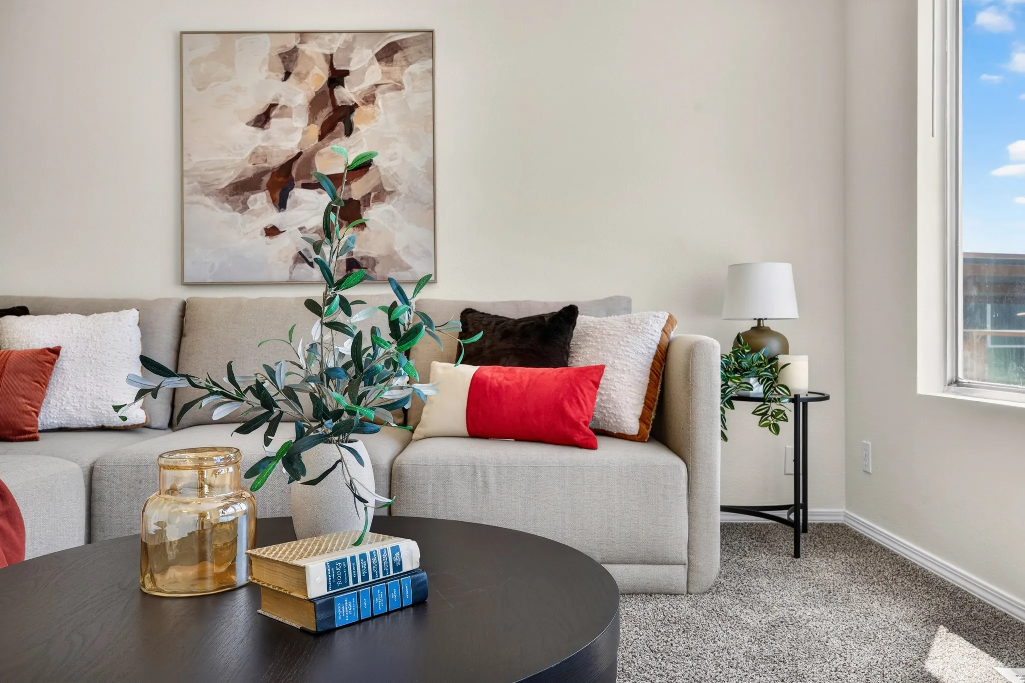 Plush carpeted flooring, a large window providing natural light, and neutral wall tones