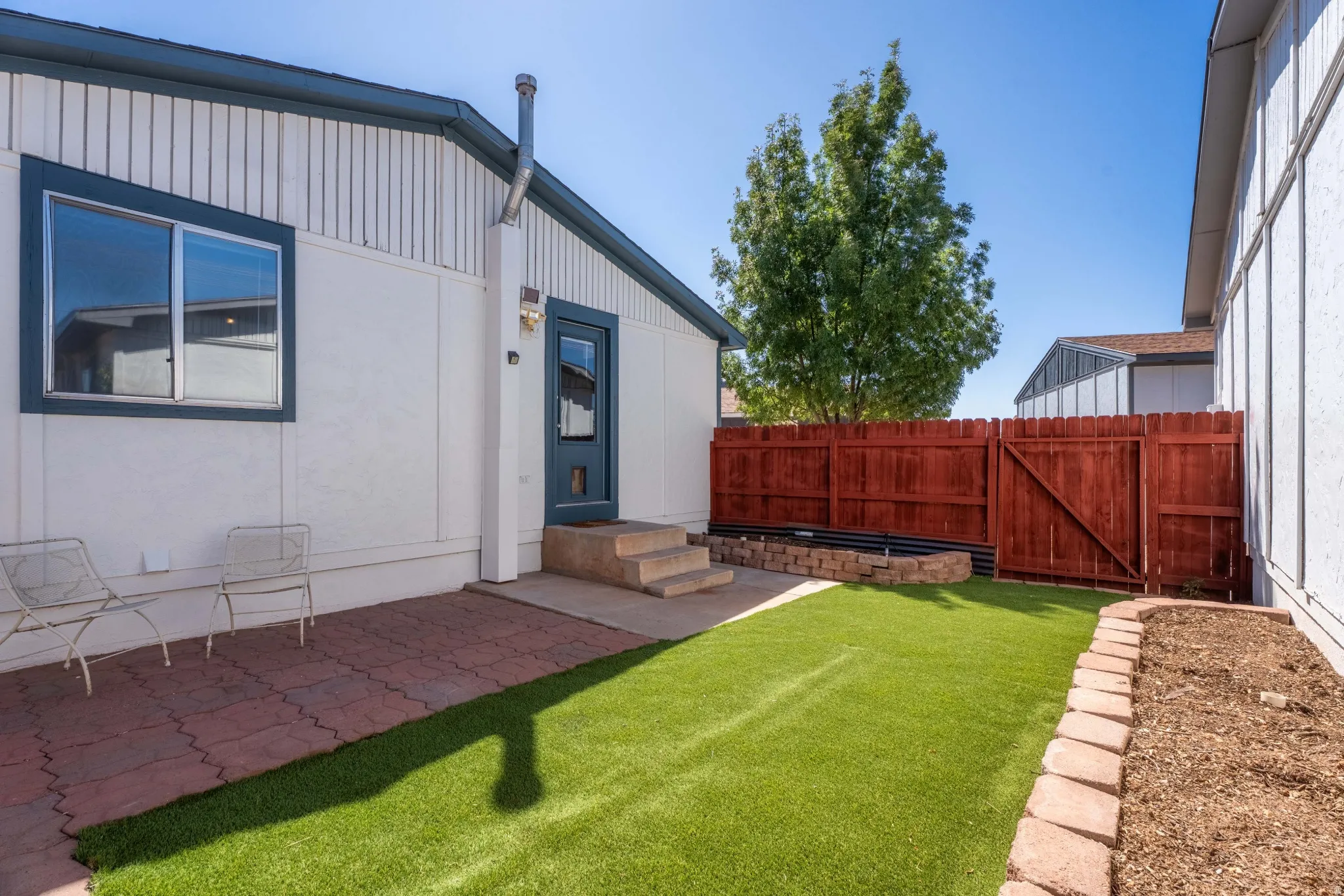 Exterior featuring a private patio, artificial turf, wood fence, and raised planter beds