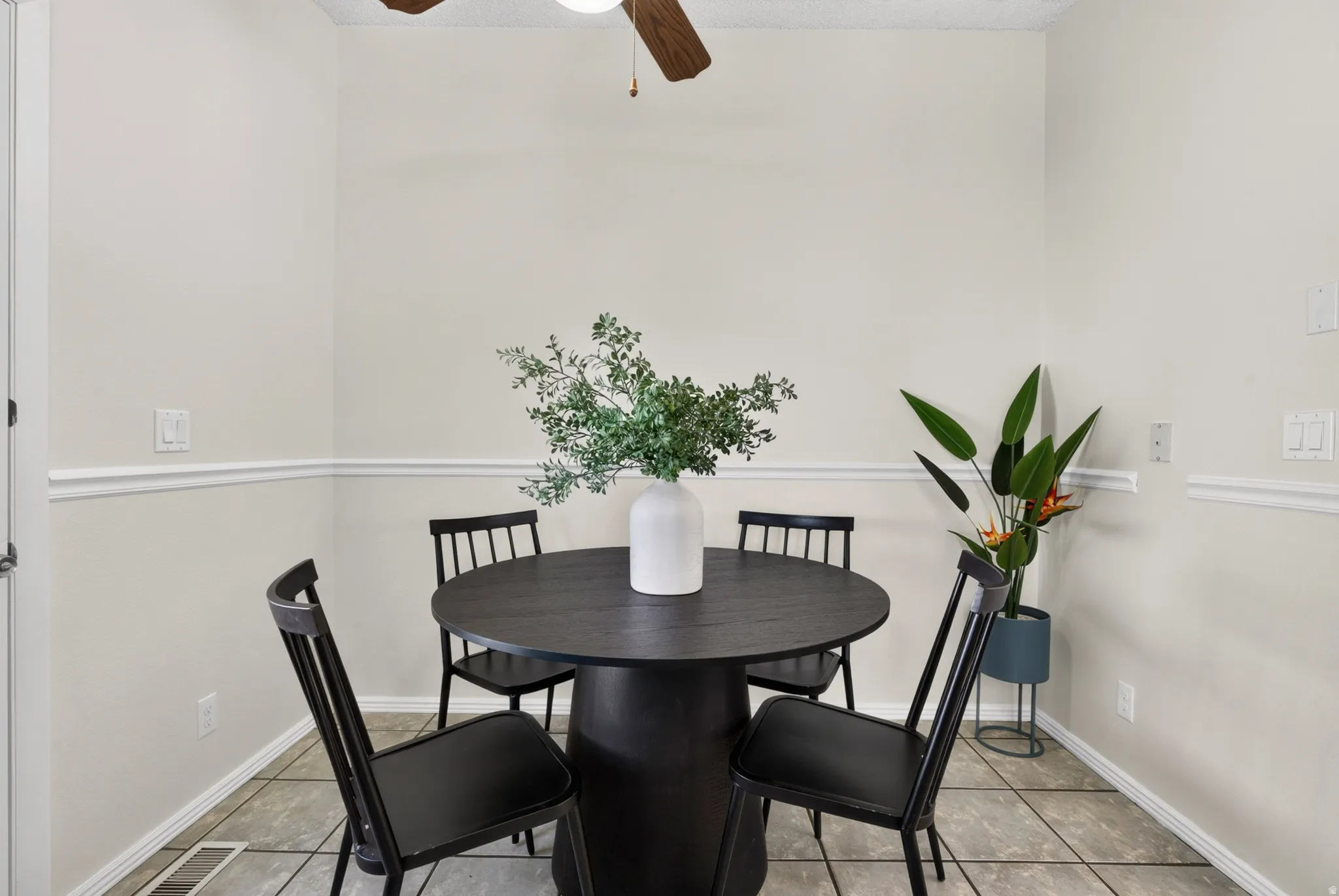 White wall paint with chair rail molding, ceiling fan, and tile flooring