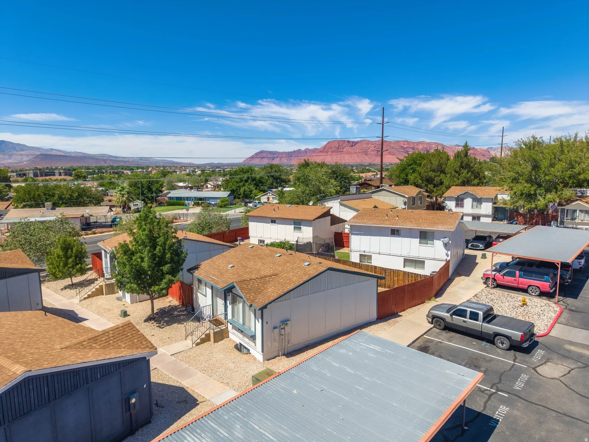 Multiple buildings with brown shingle roofs, gravel landscaping, paved walkways, and covered parking structures