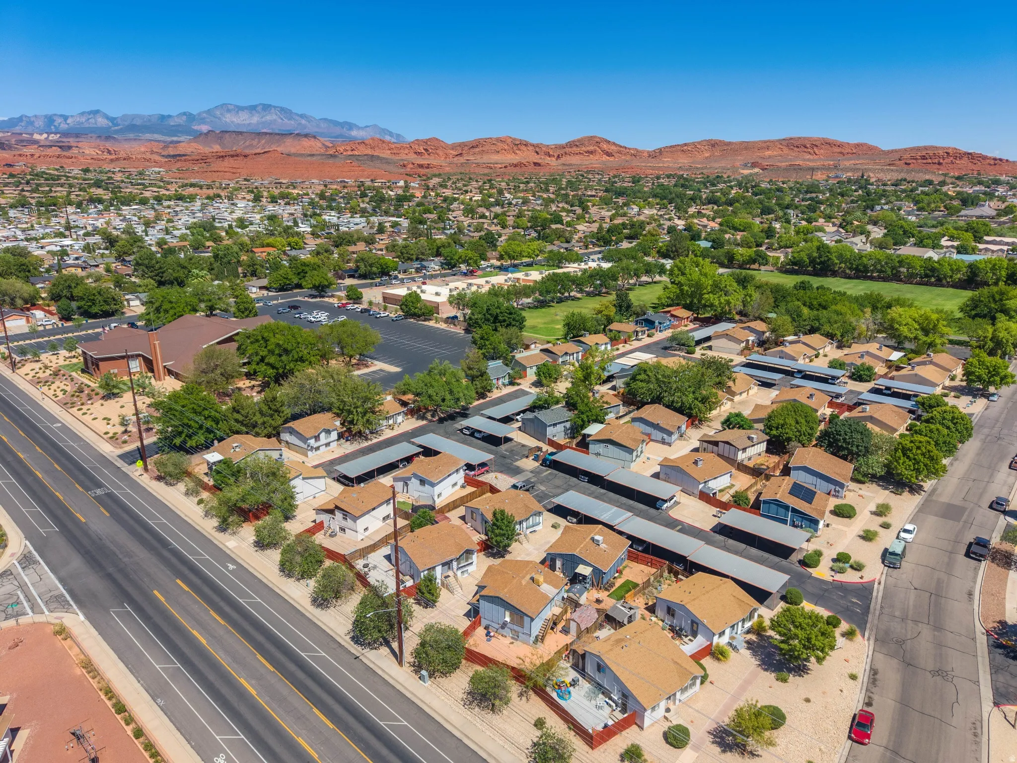 Community featuring multiple single-story residences, paved roadways, and covered parking structures