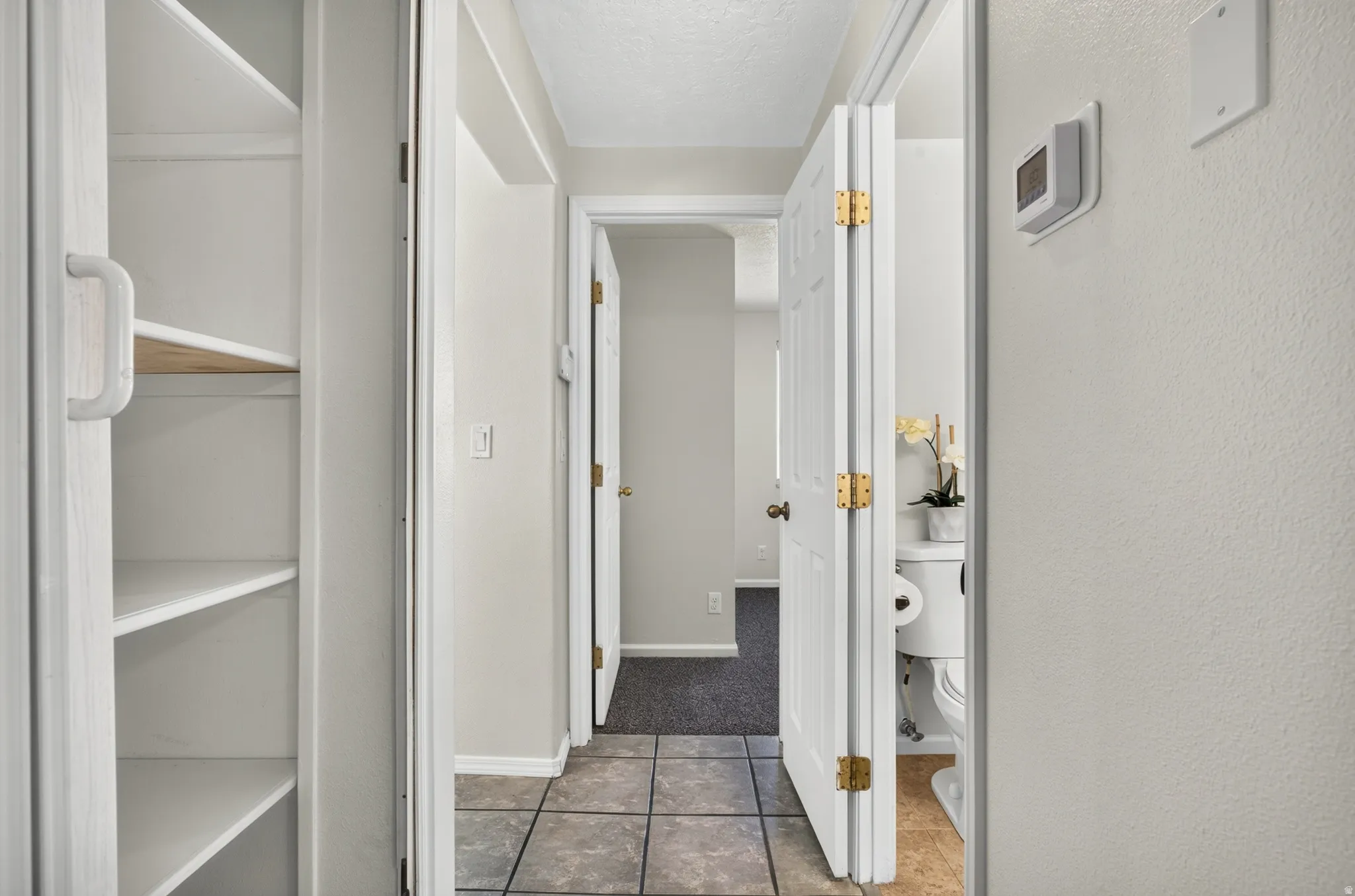 Hallway featuring tile flooring, white walls, and built-in shelving