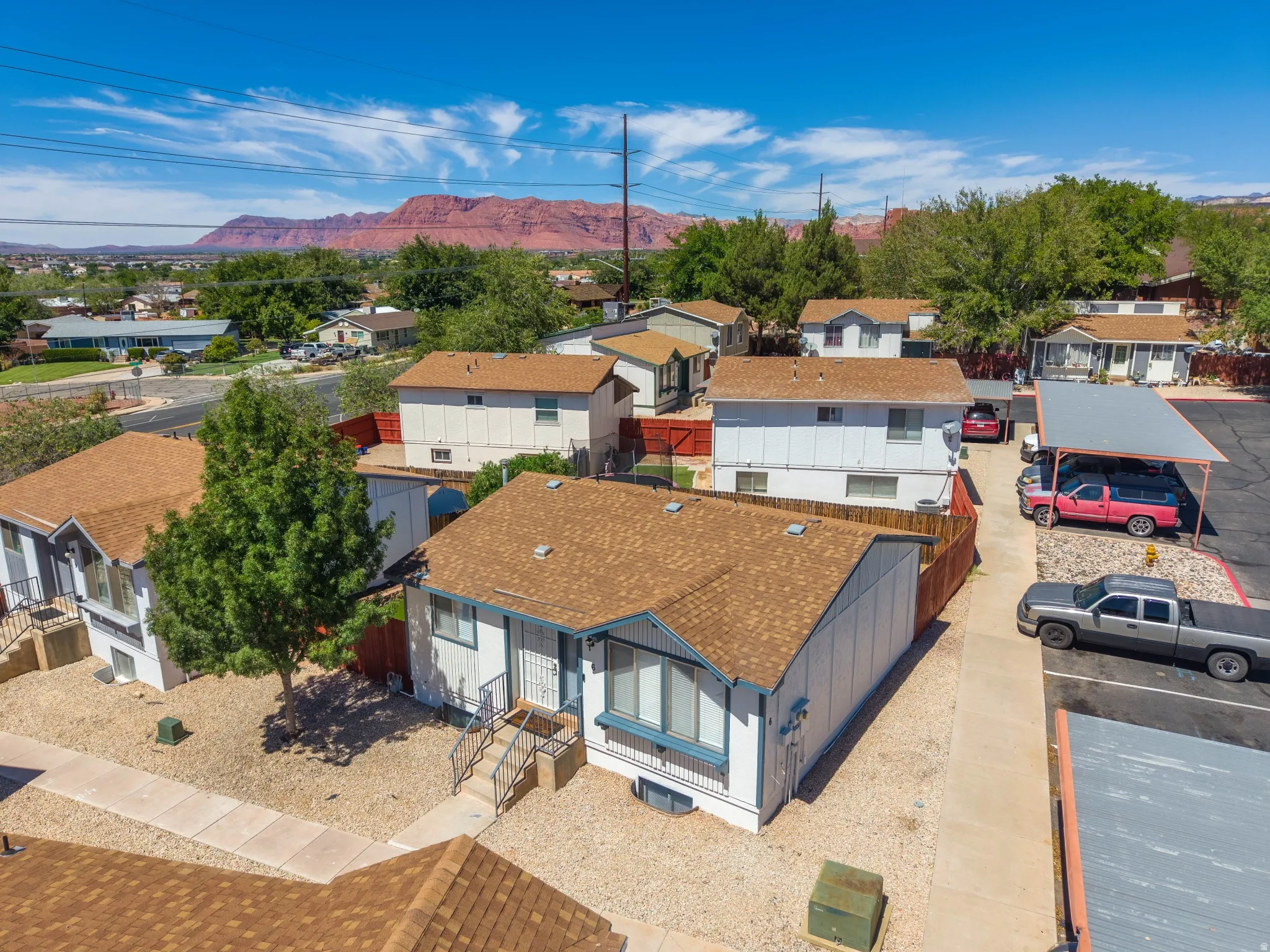 Property featuring multiple structures with brown shingle roofing, paved driveways, and carports