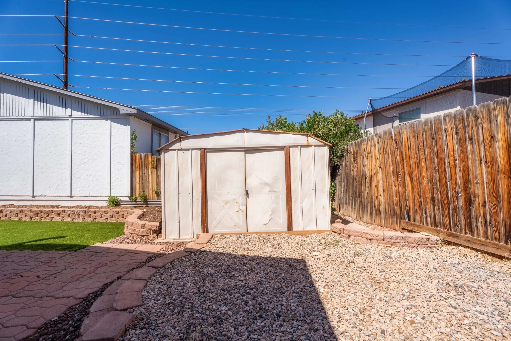 Exterior storage shed with double doors, set on a gravel surface