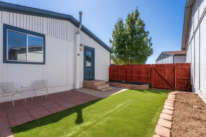 Exterior featuring a private patio, artificial turf, wood fence, and raised planter beds