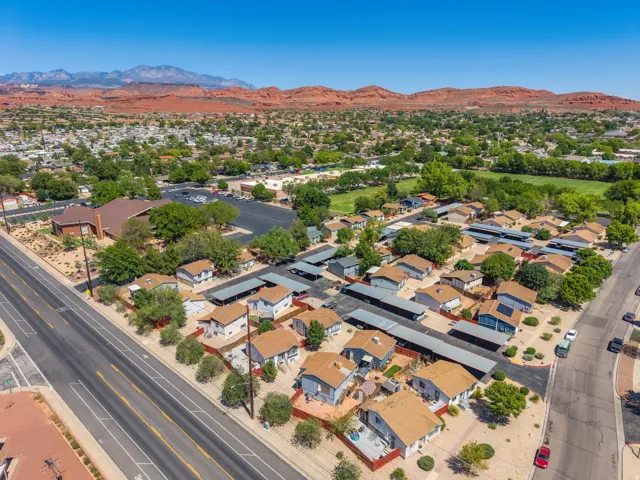 Community featuring multiple single-story residences, paved roadways, and covered parking structures