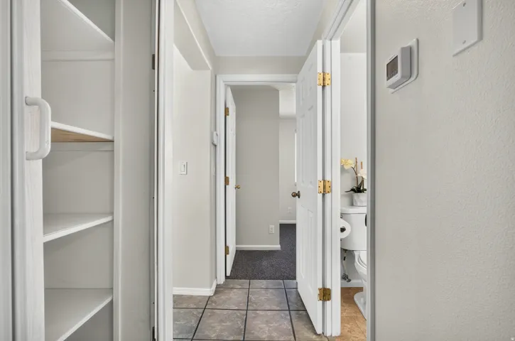 Hallway featuring tile flooring, white walls, and built-in shelving
