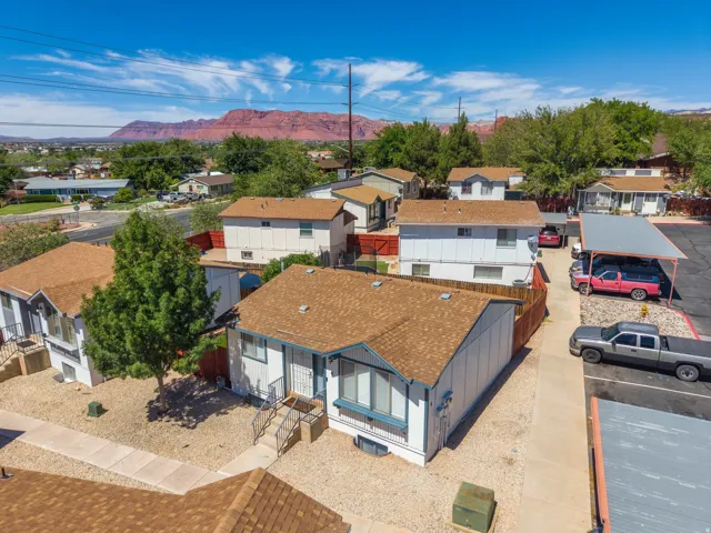 Property featuring multiple structures with brown shingle roofing, paved driveways, and carports