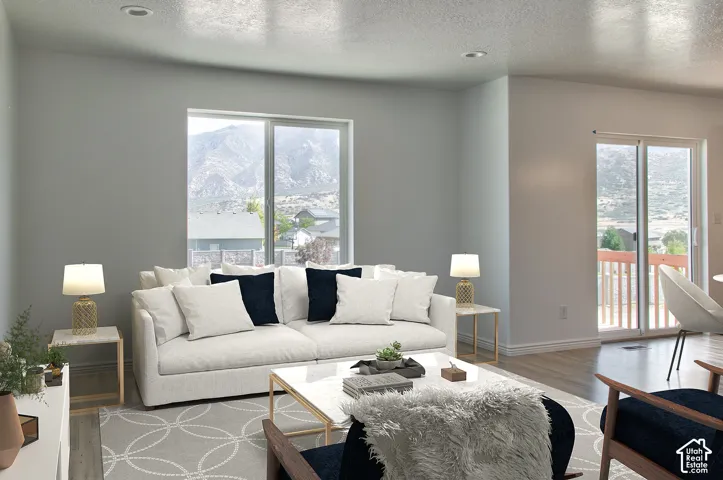 Recessed lighting, large picture windows, sliding glass door access to an exterior deck, and wood-finish flooring