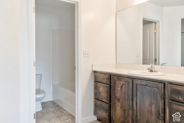 Vanity with wood-finish cabinetry, light-toned countertop, and integrated sink
