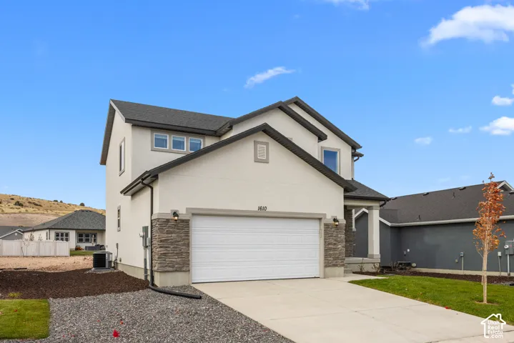 Contemporary exterior featuring a two-car garage, stone facade accents, and a covered entry