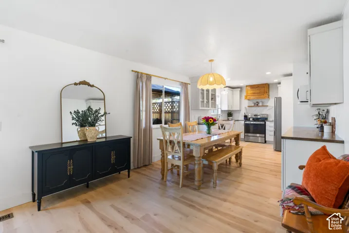 Wood-finish flooring throughout, white walls, recessed lighting, and kitchen with stainless steel appliances