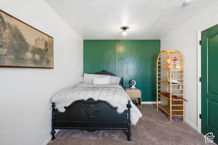 White walls with a bold green accent paneling, carpeted flooring, and a flush mount ceiling light