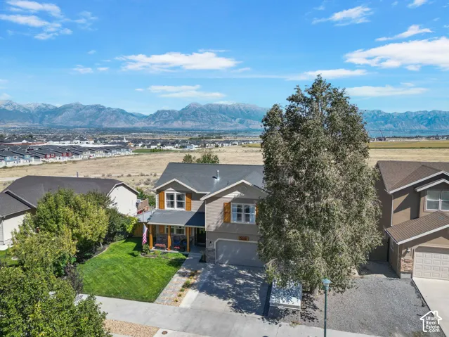 Two-story residence featuring a covered front porch, an attached garage, and a landscaped front yard with mature trees