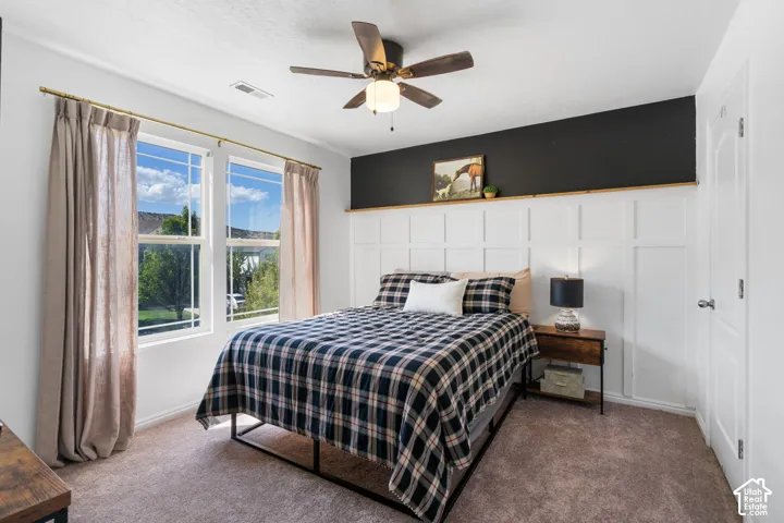 Dual pane windows, ceiling fan with integrated lighting, textured carpeting, board and batten wall detailing, and a solid core door
