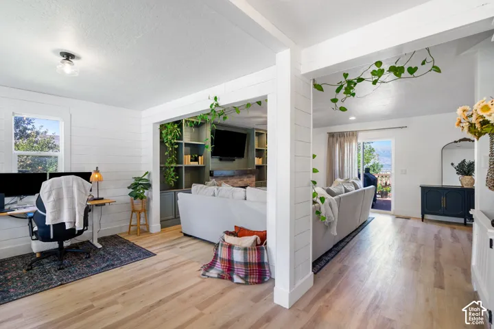 Light wood-finish flooring throughout, white shiplap wall paneling, built-in shelving, and a glass sliding door