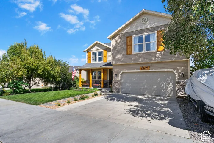 Two-story residence featuring a covered front porch with wood columns, an attached two-car garage, and a concrete driveway