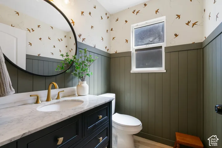 Vanity with a white countertop and oval undermount sink, gold-finish faucet, and a round black-frame mirror
