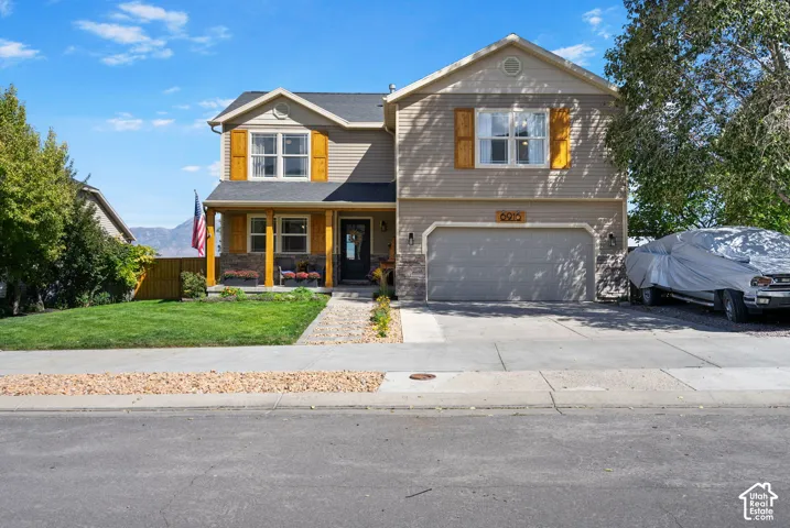 Two-story residence with a covered front porch featuring stone accents, a two-car garage, and a concrete driveway