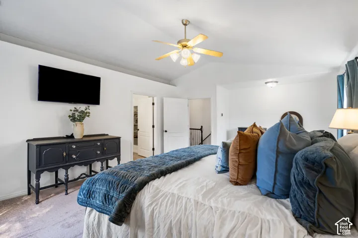 Vaulted ceiling with a ceiling fan light fixture, wall-mounted television, and paneled interior doors