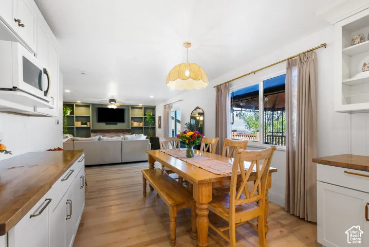 White cabinetry with wood-finish countertops, wood-finish flooring, and a dining area with a window