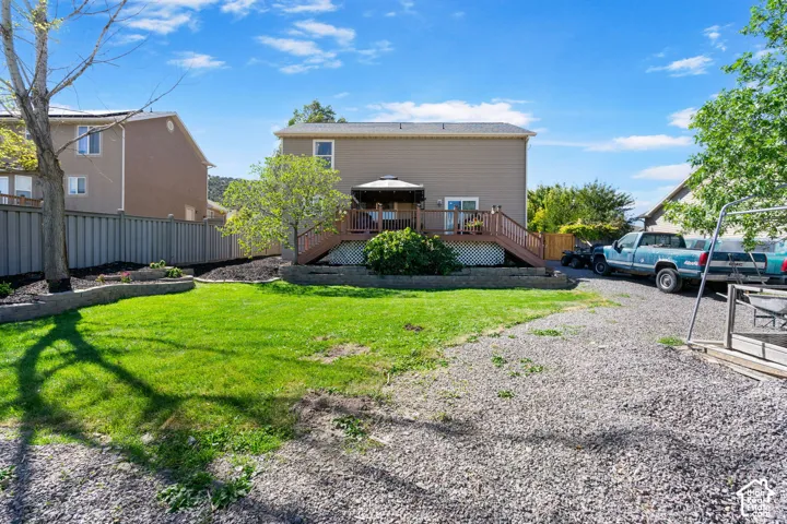 Expansive gravel parking area, elevated wood deck with railing, and a sizable lawn area