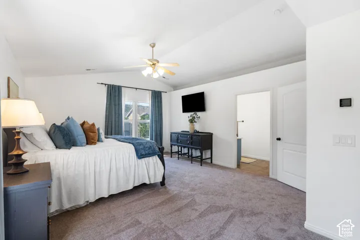 Vaulted ceiling with a ceiling fan, window with curtains, and a panel door