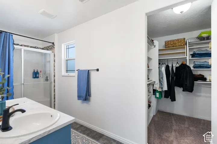 Bathroom featuring a single vanity with an oval basin, a matte black faucet, and a shower with a sliding glass door