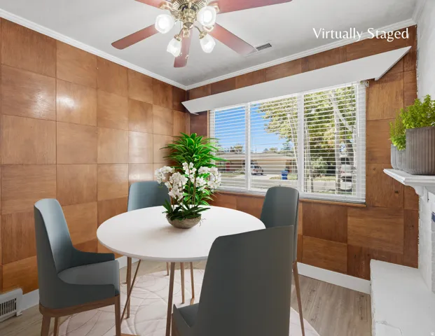 Dining room with wood-paneled wall accent, LVP flooring and a large window provides lots of natural light.  Virtually staged image.