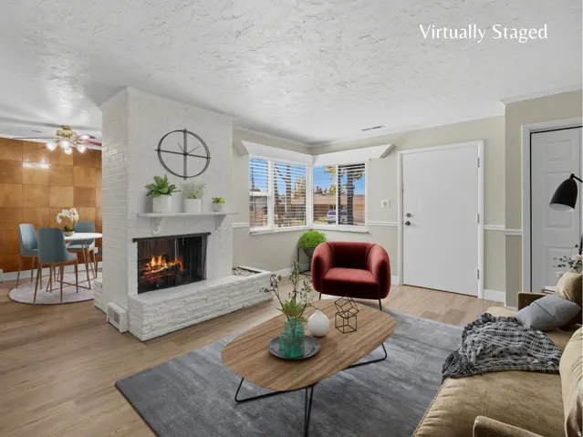 Living room with fireplace, ample natural light and updated LVP flooring.  Virtually staged image