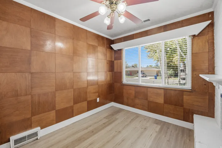 Dining room with wood-paneled wall accent, LVP flooring and a large window provides lots of natural light