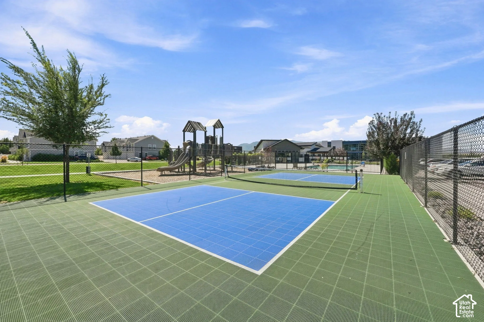 Multiple sports courts, a playground structure, and expansive green space