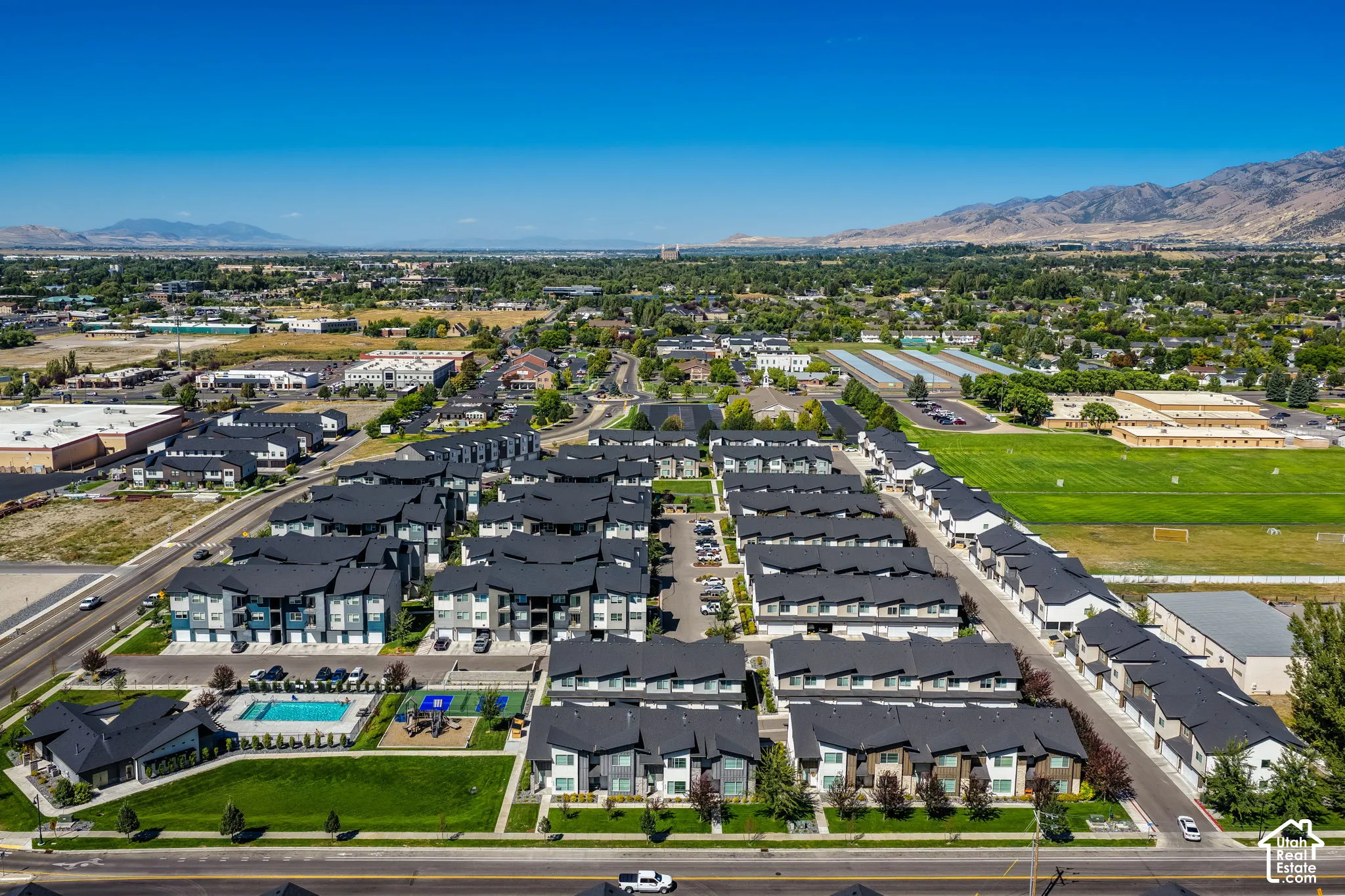 Community with multiple multi-story buildings, dark roofs, and light-colored siding