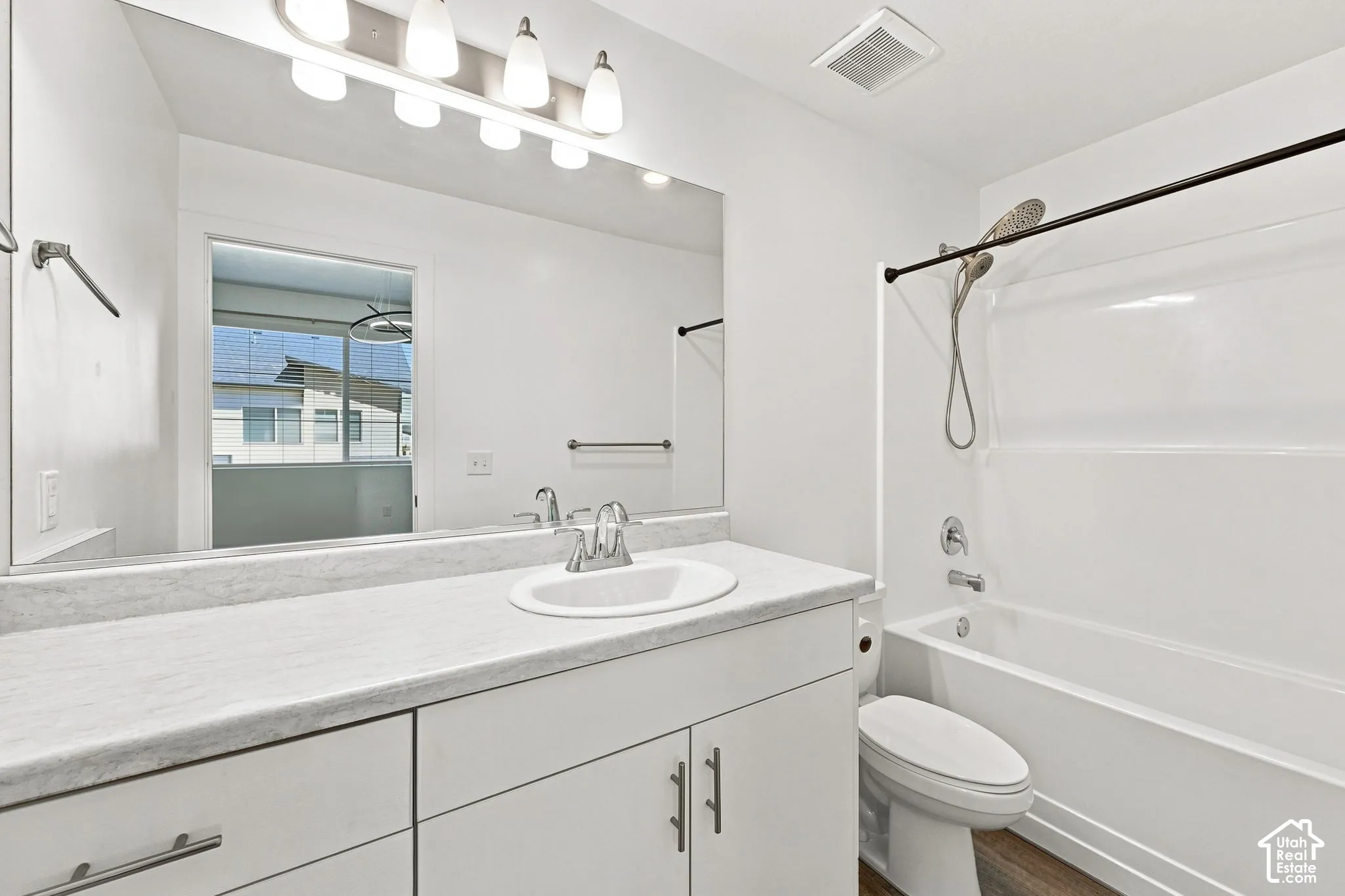 White vanity with a single basin sink, light-colored countertop, and chrome faucet