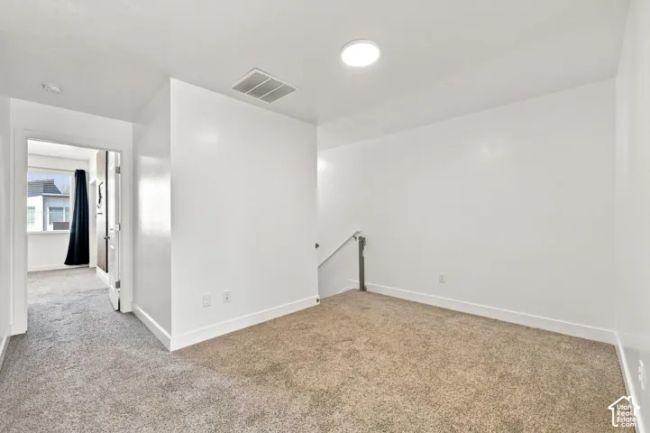 Light-colored carpeting, white walls, recessed ceiling light, and a white ceiling