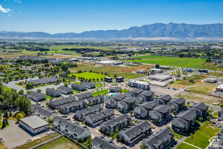 Community with multi-story residences, surrounded by green spaces and distant mountains
