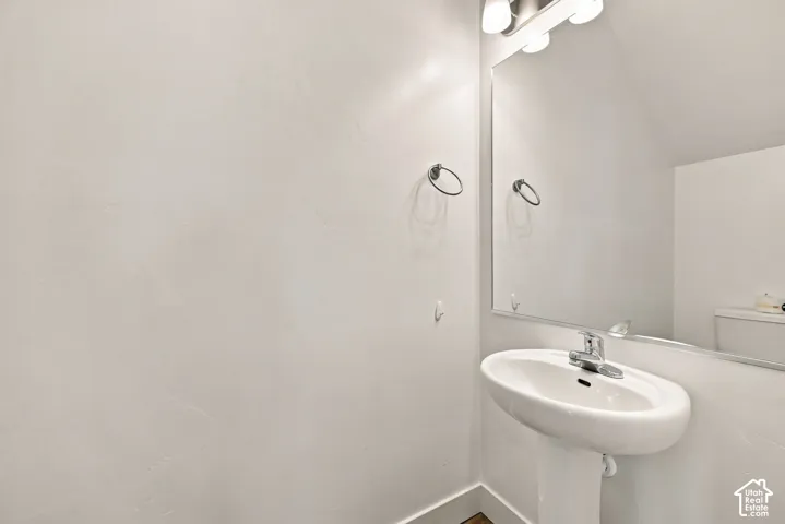 Pedestal sink with chrome faucet, wall-mounted mirror, and vanity light fixture