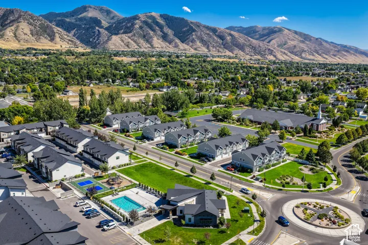 Community featuring a swimming pool, sports court, and open green spaces, surrounded by a mountainous backdrop