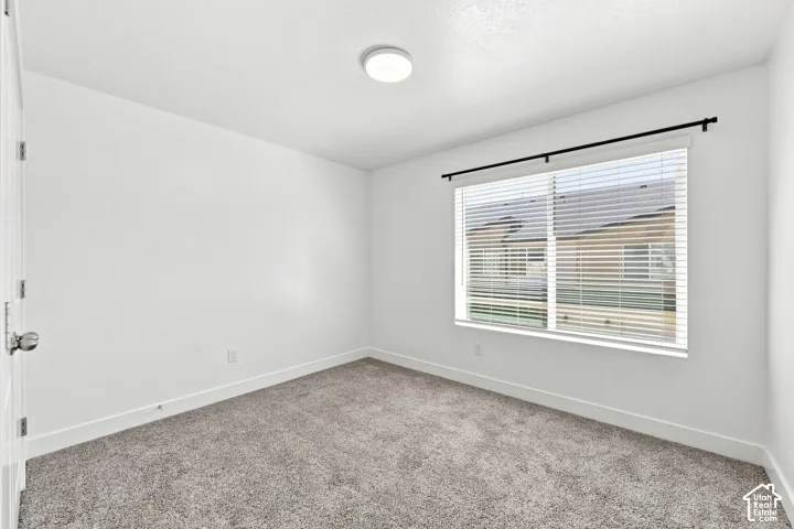 Wall-to-wall carpeting, white walls, window with horizontal blinds, and a flush mount ceiling light
