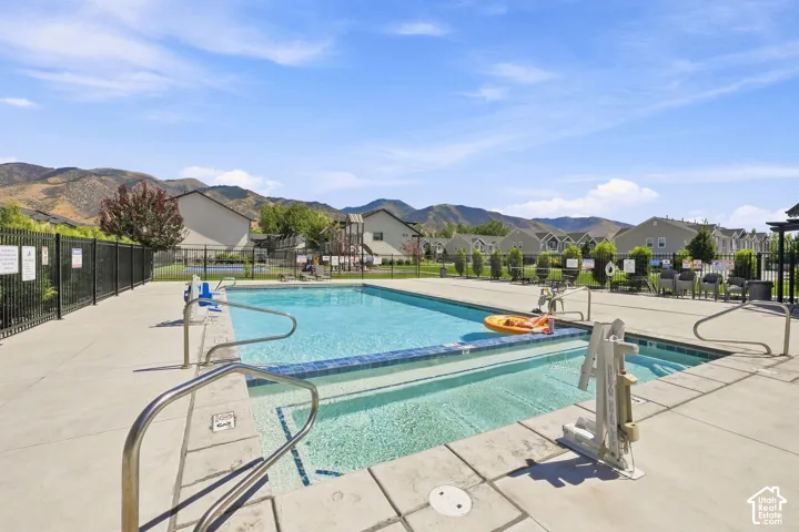 Community swimming pool with surrounding concrete decking, metal handrails, and a black perimeter fence