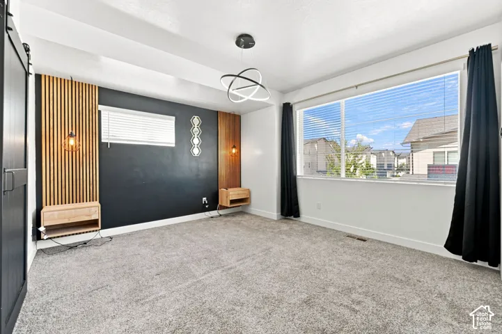 Wide window with blinds, wood-finish accent wall paneling, built-in floating nightstands, and a modern ceiling light fixture