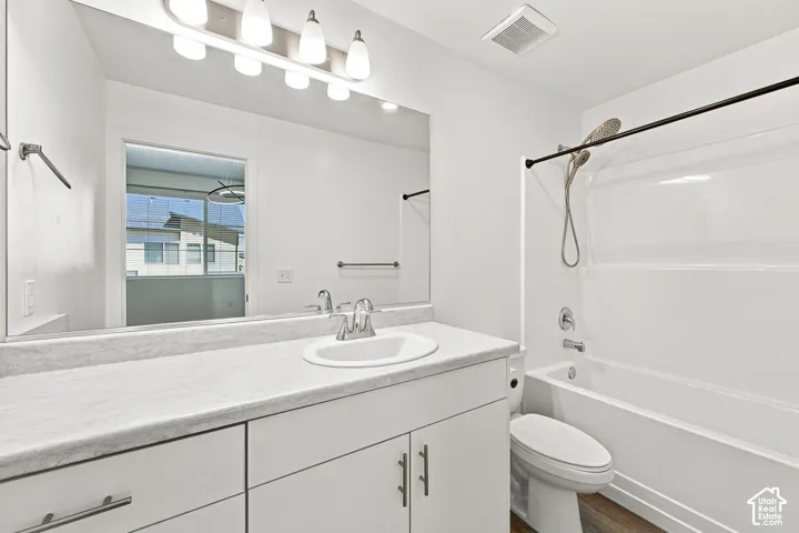 White vanity with a single basin sink, light-colored countertop, and chrome faucet
