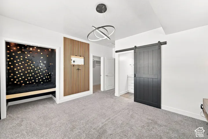 Built-in alcove seating, contemporary chandelier, slatted wood-finish wall accent, dark-tone barn door, and light gray carpeting