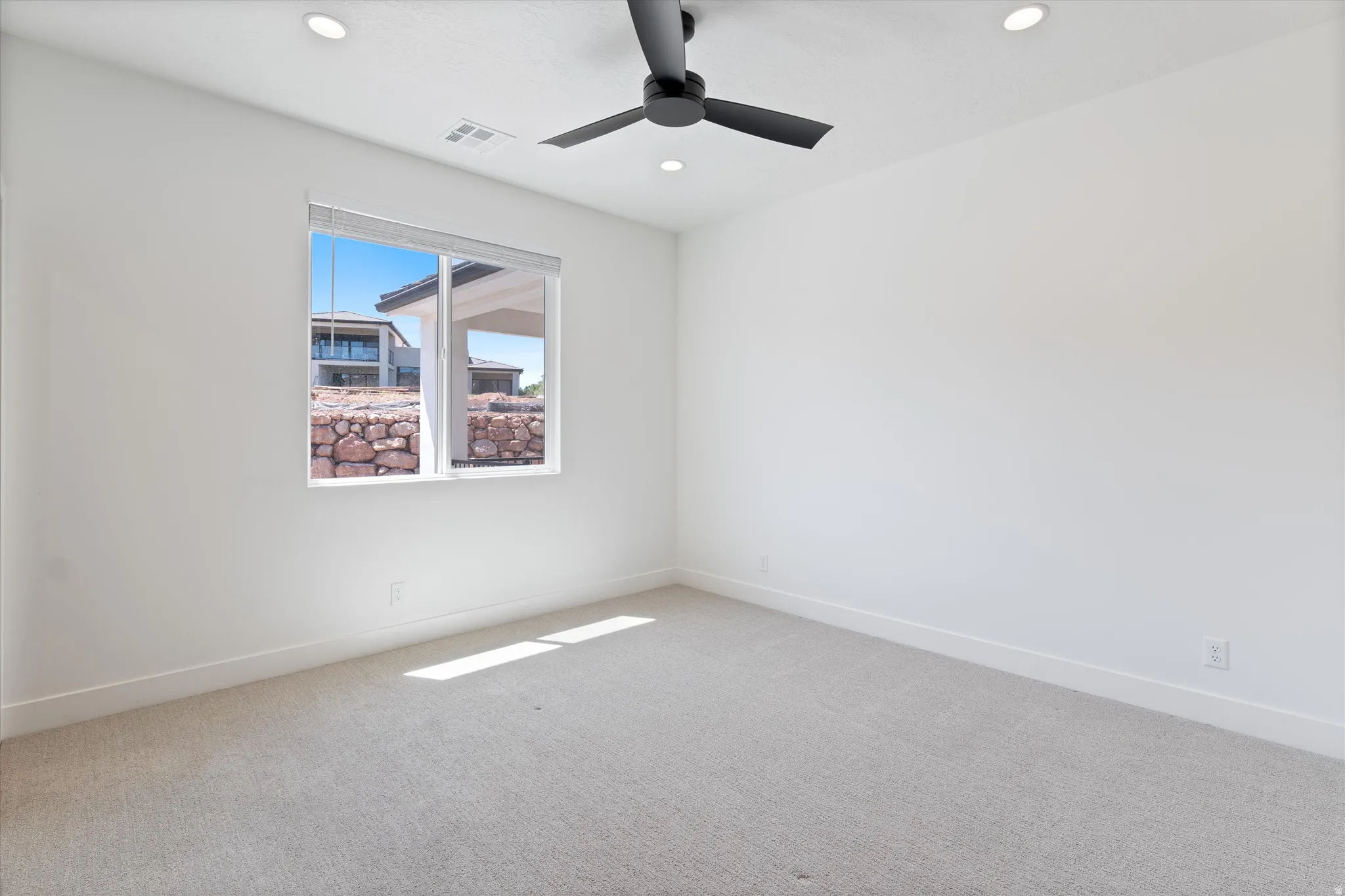 Neutral-toned carpeting, recessed ceiling lighting, and a dark-toned ceiling fan