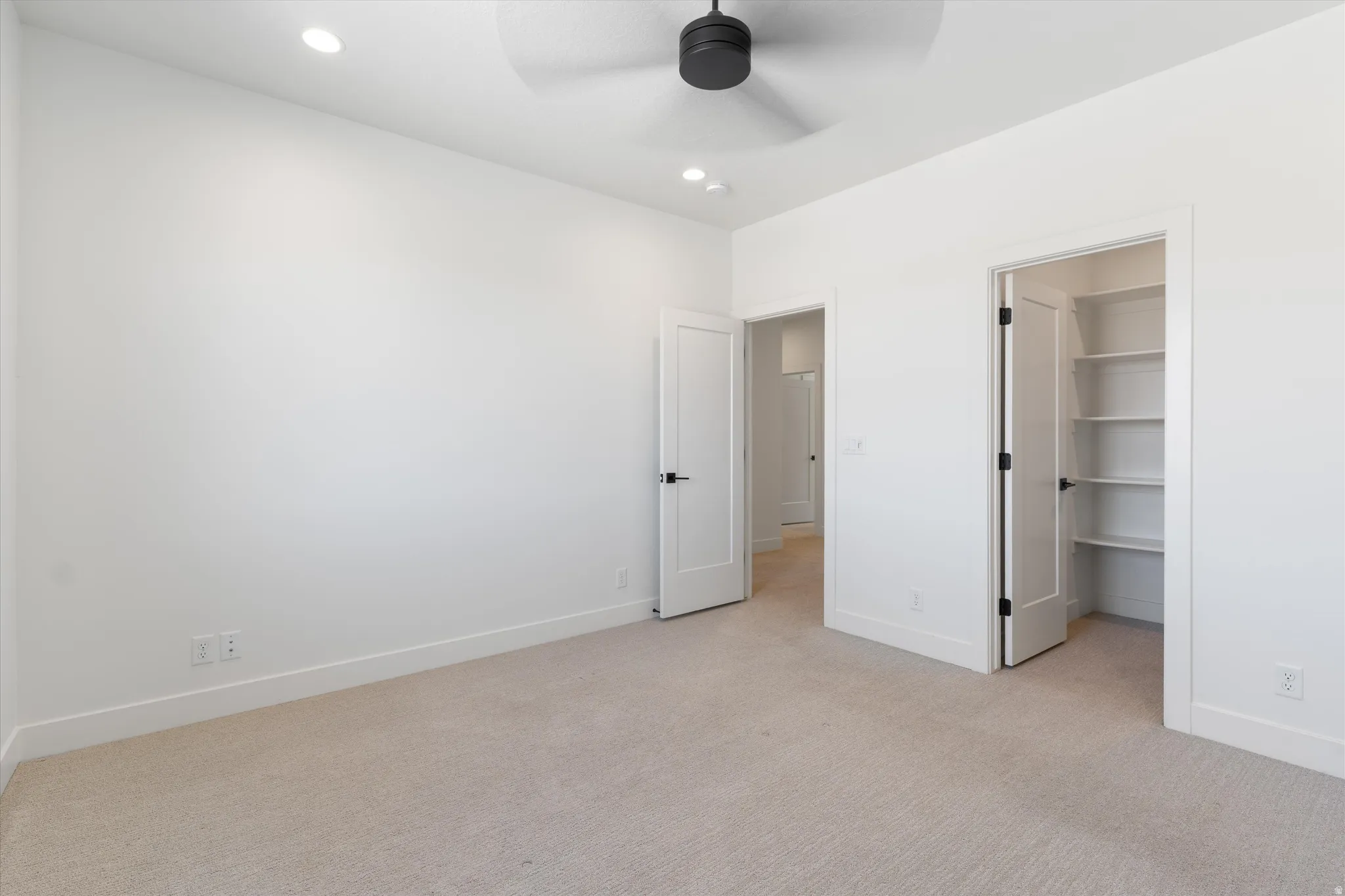 Recessed lighting, ceiling fan, plush carpeting, built-in shelving, and contemporary hardware