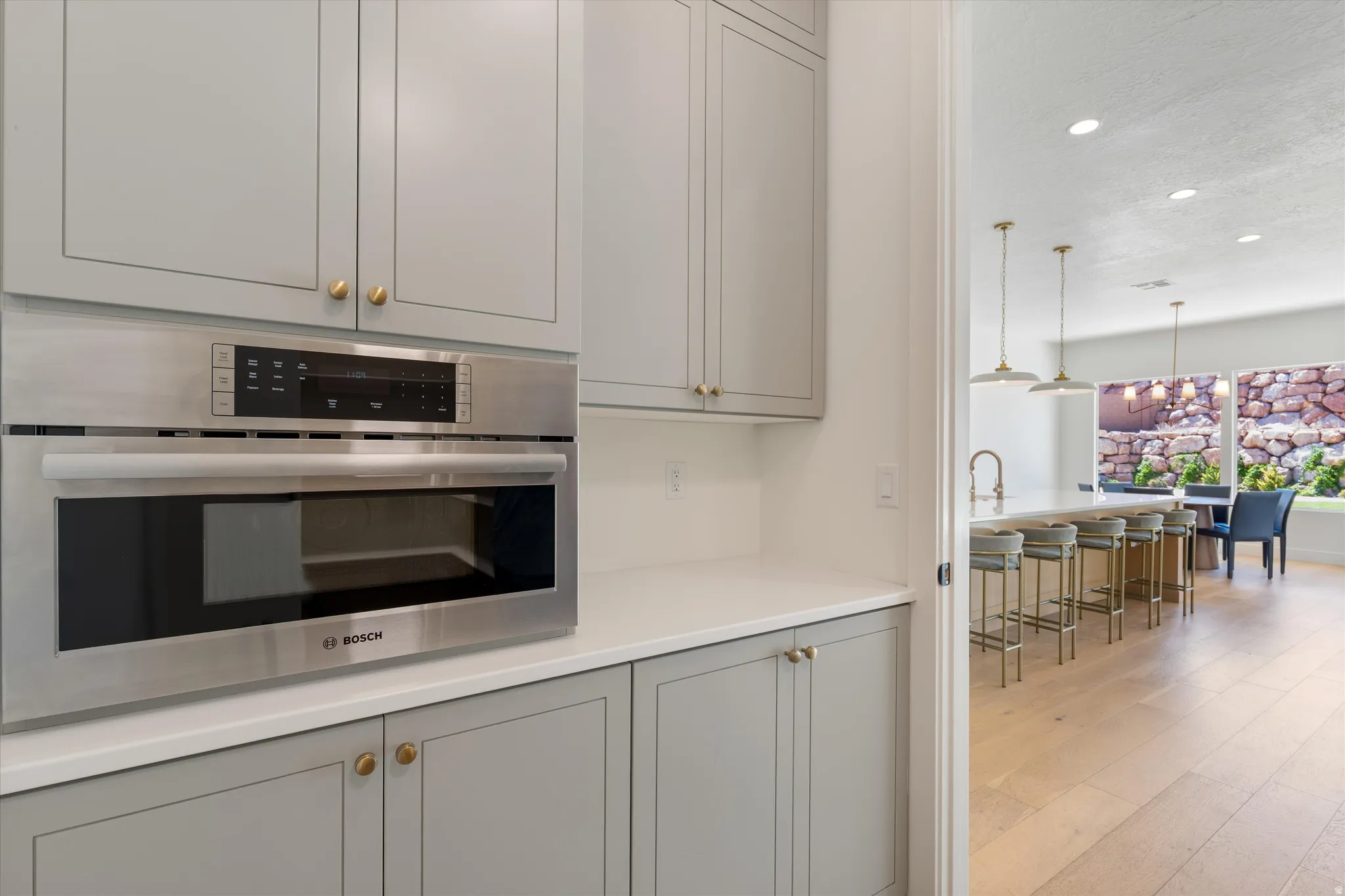 Built-in stainless steel microwave and oven combination with light gray cabinetry and white countertops