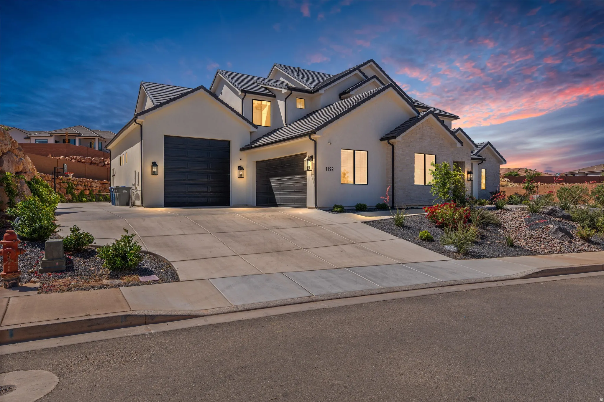 Contemporary exterior architecture with a multi-gabled roof, stone façade accents, dual garage doors, and front landscaping