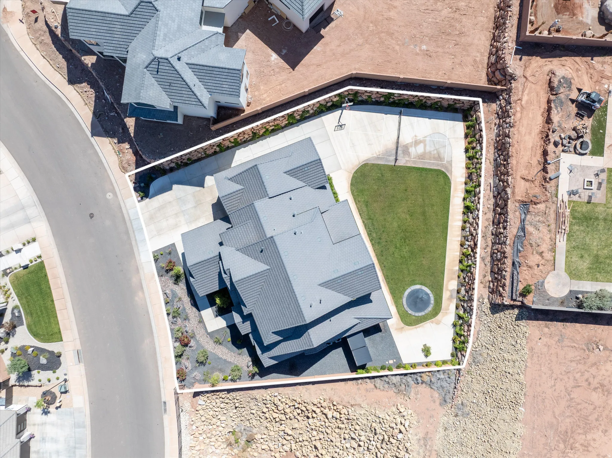 Modern roof design, concrete driveway, manicured lawn, established landscaping, and basketball hoop