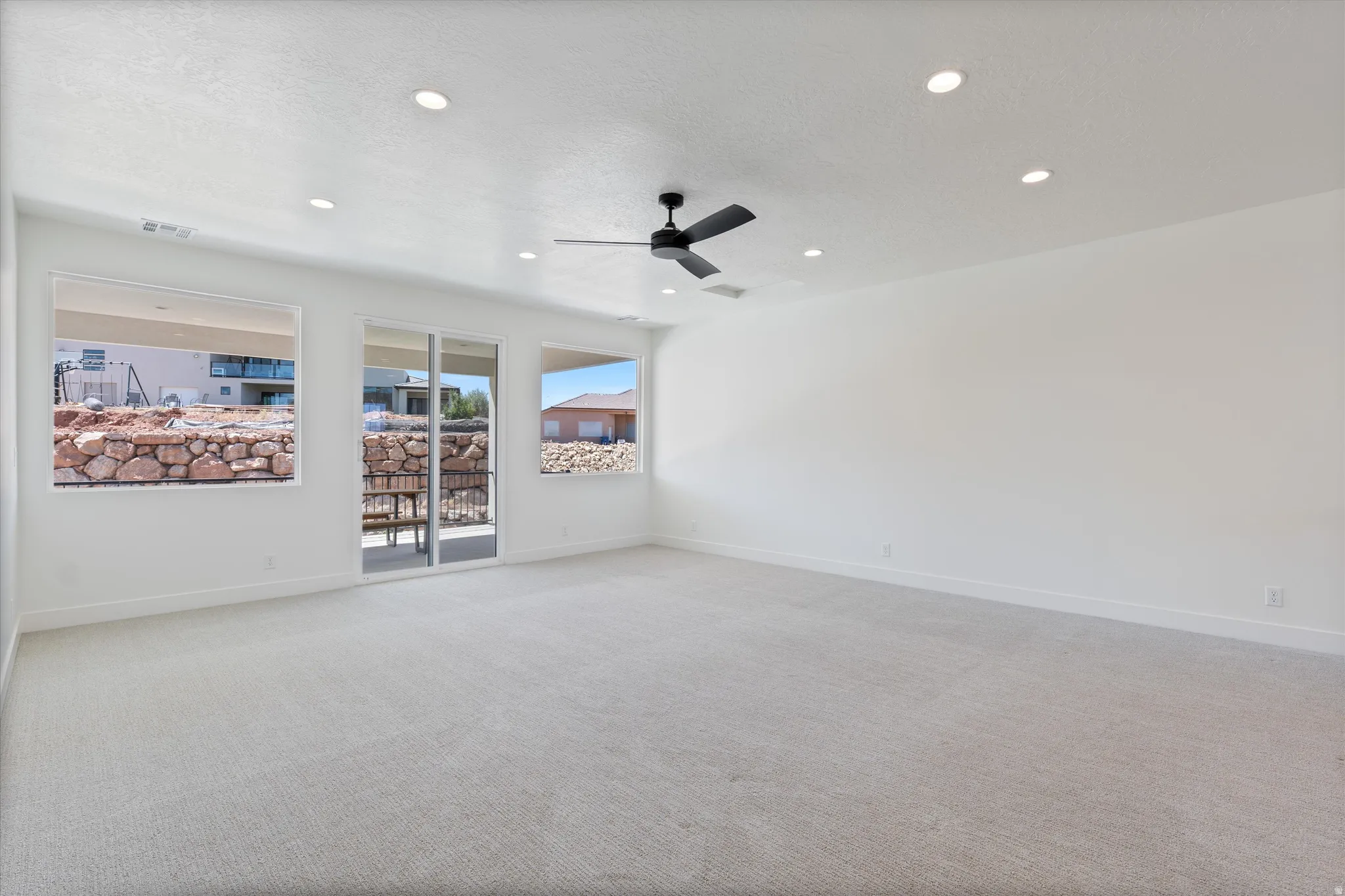 Expansive room featuring light-colored carpeting, recessed lighting, and a ceiling fan