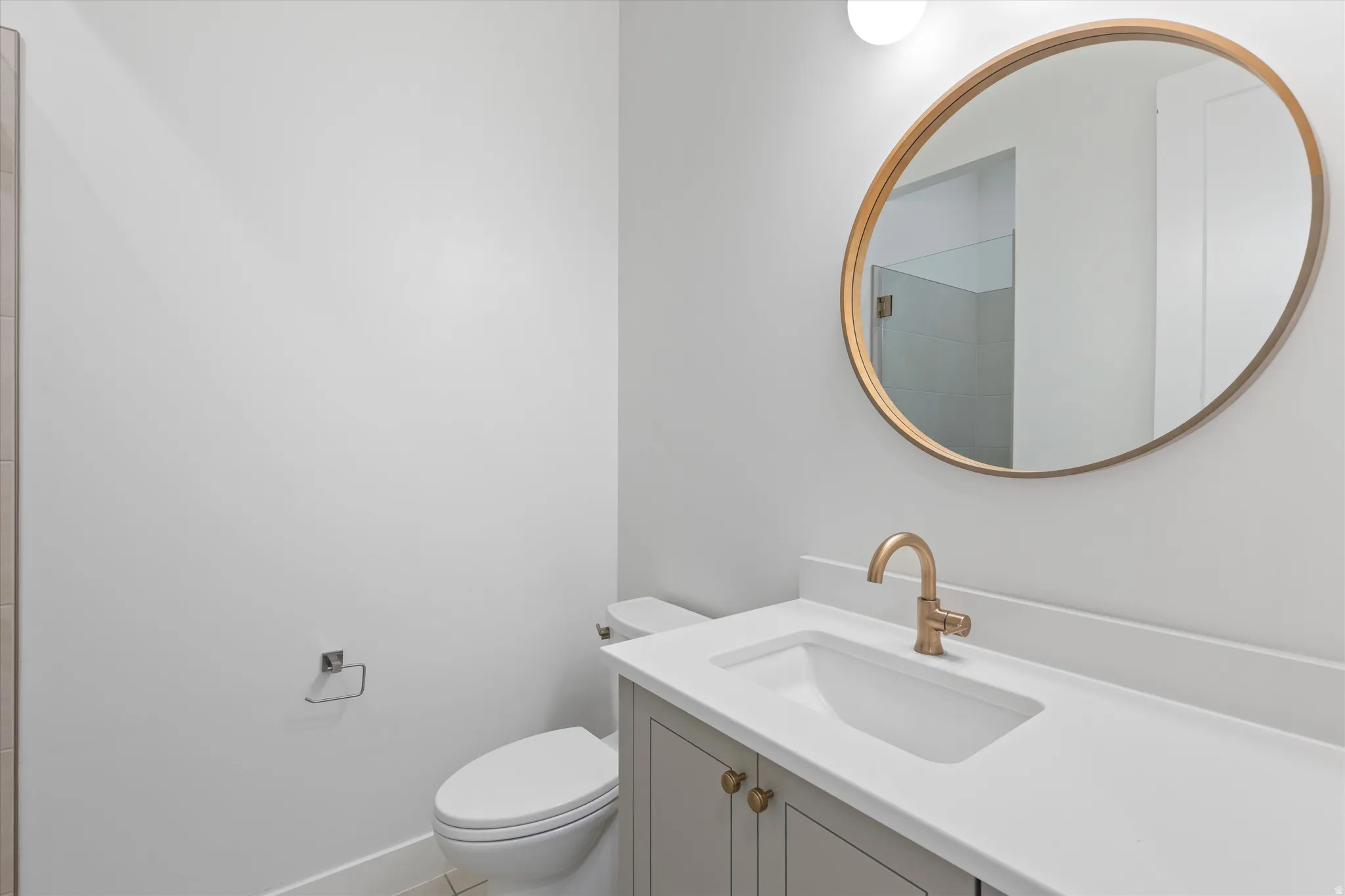 Vanity with integrated sink, gold-finish faucet, and gold-finish round mirror